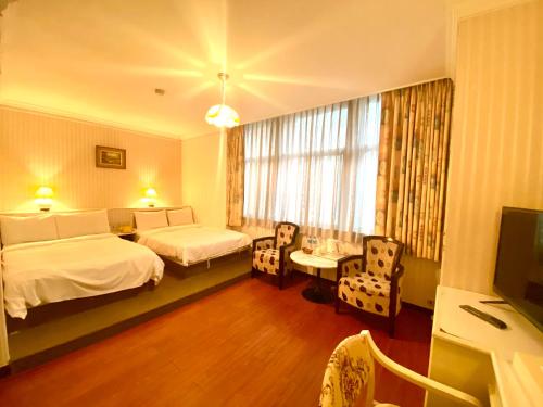 a hotel room with two beds and a television at Li Hua Hotel in Taoyuan
