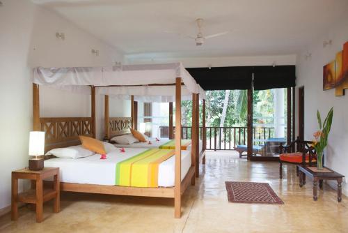 1 dormitorio con cama con dosel y balcón en Ratnakara, en Dondra East
