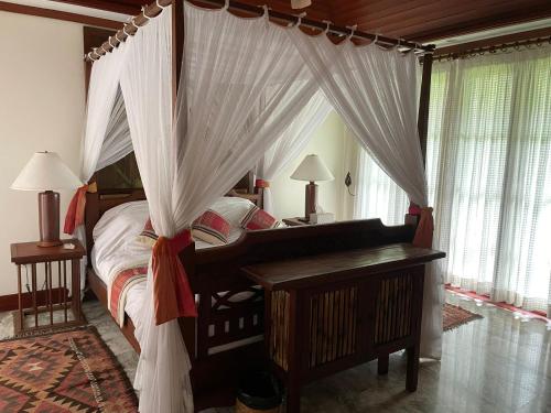 a bedroom with a canopy bed with a desk and a piano at Ban Na in Satuk