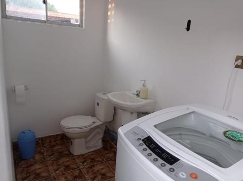 a white bathroom with a toilet and a sink at Cómoda casa con piscina in Arica