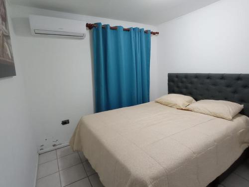 1 dormitorio con 1 cama con cortina azul en Cómoda casa con piscina en Arica
