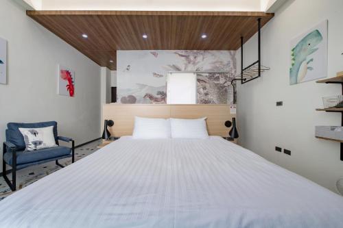 a bedroom with a large bed and a blue chair at Long Stay Here in Tainan