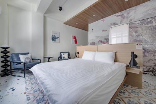 a bedroom with a large white bed and a mirror at Long Stay Here in Tainan