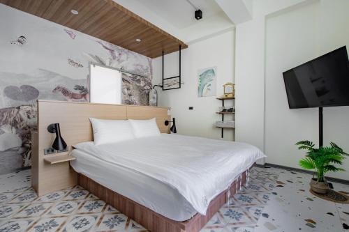 a bedroom with a bed and a flat screen tv at Long Stay Here in Tainan
