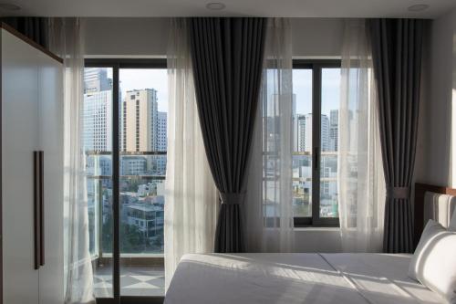 a bedroom with a bed and a large window at GoldCoast Hotel Nha Trang in Nha Trang
