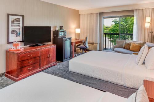 a hotel room with a bed and a flat screen tv at Courtyard by Marriot Cranbury South Brunswick in Cranbury