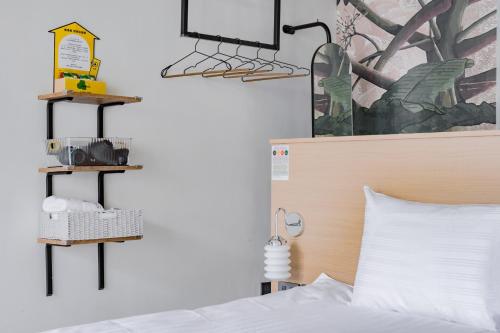 a bedroom with a bed with two shelves on the wall at Long Stay Here in Tainan