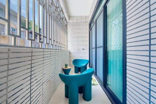 a room with two blue chairs in front of a window at Long Stay Here in Tainan