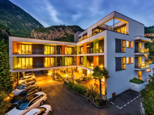 a building with cars parked in a parking lot at Active & Family Hotel Gioiosa in Riva del Garda