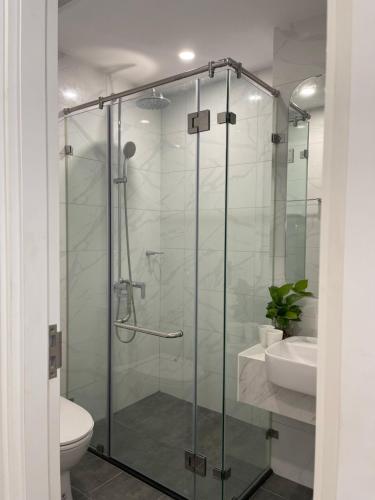 a bathroom with a glass shower with a toilet and a sink at Vinhome Smartcity - Căn hộ cao cấp full tiện ích TTA in Hanoi