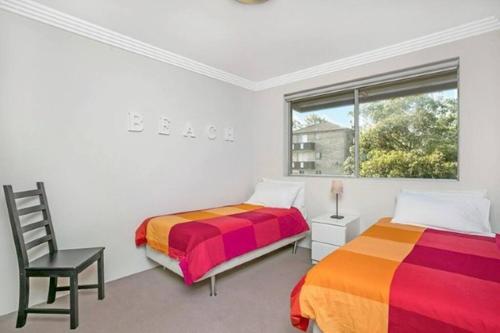 2 camas en una habitación con silla y ventana en COOGY - Coogee Gem: Short Walk To Coogee Beach, en Sídney