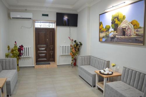 een woonkamer met twee banken en een tafel en een deur bij Hostel DANEXAN APA in Nukus