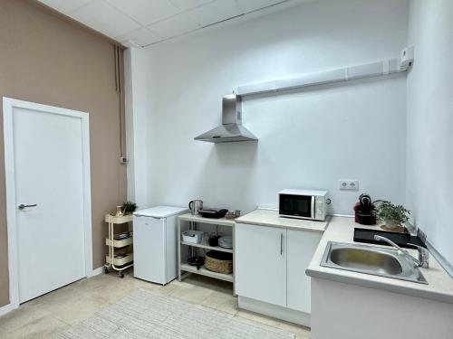a white kitchen with a sink and a microwave at The Valencia Stop in Valencia