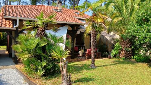 a house with palm trees in front of it at Maison Candide 3 chambres 1 mezzanine in Capbreton