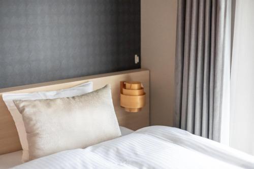 a bed with a white pillow next to a window at Oyado Kawaramachi Gojo（御宿 河原町五条） in Kyoto