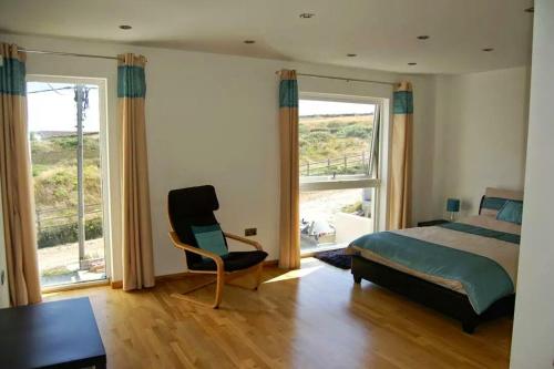 a bedroom with a bed and a chair and a window at Cellar Cove in Perranporth
