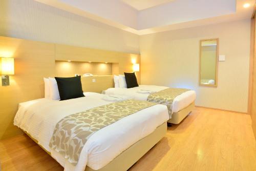 a hotel room with two beds and a mirror at Moon Ocean Ginowan Hotel & Residence in Ginowan