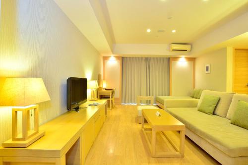 a living room with a couch and a tv at Moon Ocean Ginowan Hotel & Residence in Ginowan