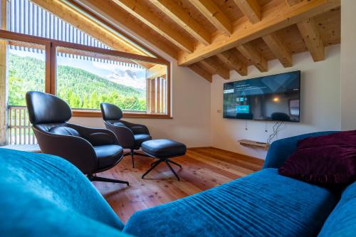 a living room with a couch and chairs and a tv at Appartamento GreenWood in Vodo Cadore