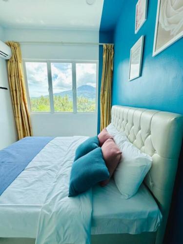 a blue bedroom with a bed with a window at Summer View Apartment + Sky pool in Kuah