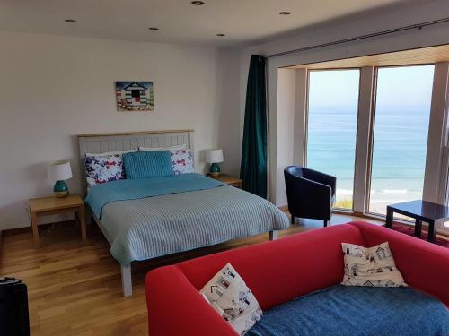 a bedroom with a bed and a red couch at CELLAR COVE in Perranporth