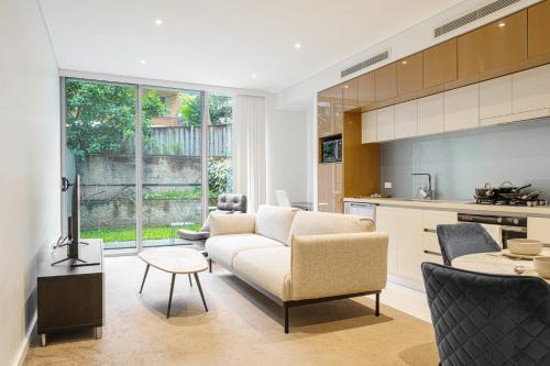 a living room with a couch and a kitchen at Modern Urban Retreat 1BR Apt near Chatswood in Sydney