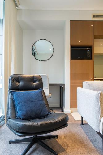 a leather chair with a blue pillow in a living room at Modern Urban Retreat 1BR Apt near Chatswood in Sydney