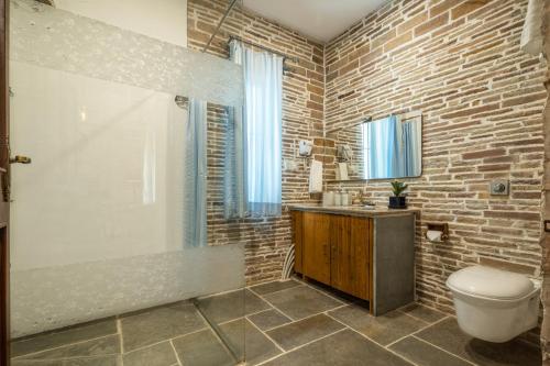 a bathroom with a toilet and a brick wall at Moonstone, Bhopal, amã Stays & Trails in Shamsgarh