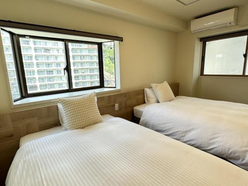 two beds in a small room with two windows at Grandview Atami Private Hot Spring Condominium Hotel in Atami