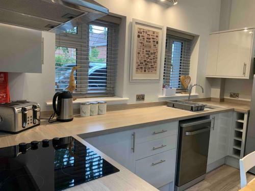 a kitchen with white cabinets and a counter top at Hedgehog Cottage in Bury Saint Edmunds