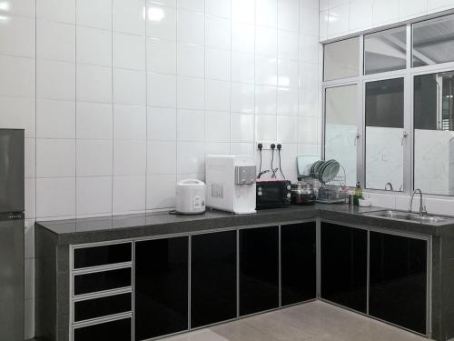 a kitchen with a counter with a sink and a microwave at IMPIAN STAY #2 Semi Bungalow House in Kuah