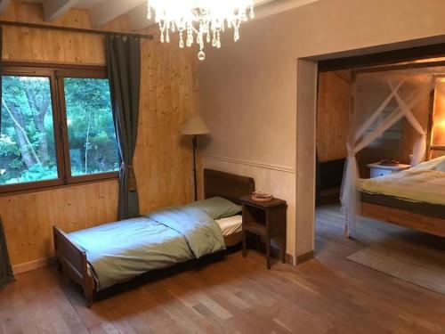 - une chambre avec un lit et un lustre dans l'établissement Charming country house in the forest, with heated pool, à Cerdon