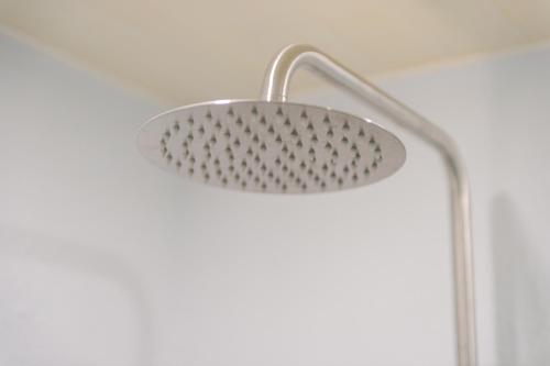 a shower head in a bathroom with a white wall at Long Stay Here in Tainan
