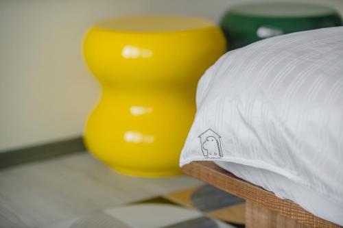 a yellow vase sitting next to a bed with a pillow at Long Stay Here in Tainan