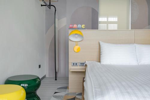 a bedroom with a bed and a lamp and a table at Long Stay Here in Tainan
