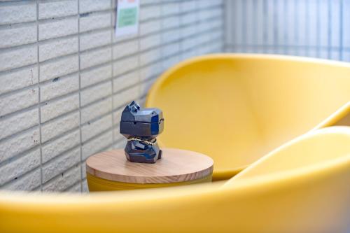 a blue toy robot sitting on a yellow chair at Long Stay Here in Tainan