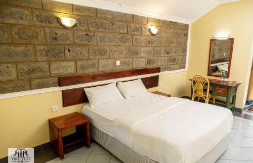 1 dormitorio con cama blanca, mesa y escritorio en EQUINE RESORT en Gitura