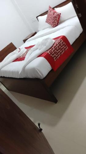 Una cama con mantas rojas y blancas y almohadas. en RD HOTEL en Erode