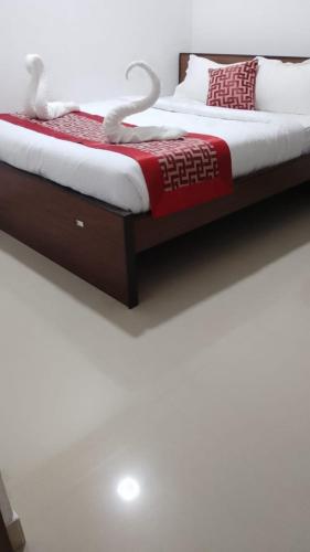 1 dormitorio con 1 cama con manta roja y blanca en RD HOTEL en Erode
