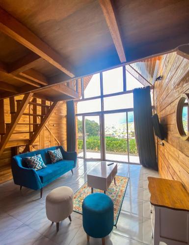 Godieng Cabin 2 في Diyeng: غرفة معيشة مع أريكة زرقاء ونافذة كبيرة