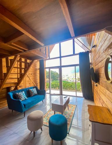 a living room with a blue couch and a large window at Godieng Cabin 2 in Dieng