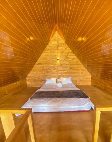 a bed in a wooden cabin with a wooden ceiling at Godieng Cabin 2 in Dieng