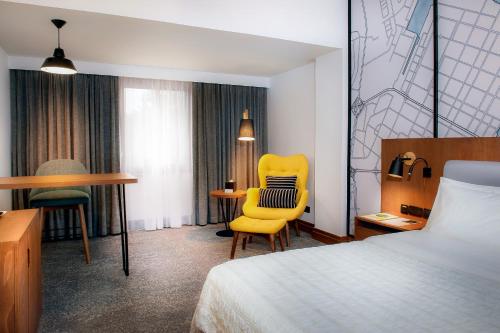阿布達比的住宿－阿布扎比艾美假村酒店，酒店客房配有一张床、一张黄色椅子和一张书桌