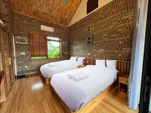 a bedroom with two beds and a brick wall at Villa Đường Lâm- Sơn Tây in Hanoi