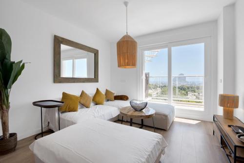 sala de estar blanca con sofá y ventana en Real de Ifach - Atico, en Empedrola