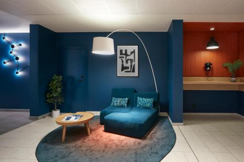 a blue room with a blue chair and a table at Aparthotel Adagio Access La Défense Puteaux in Puteaux