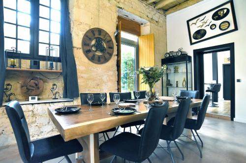 une salle à manger avec une table, des chaises et une horloge dans l'établissement Galerie - Ancienne galerie de peinture sur le port, à Dinan