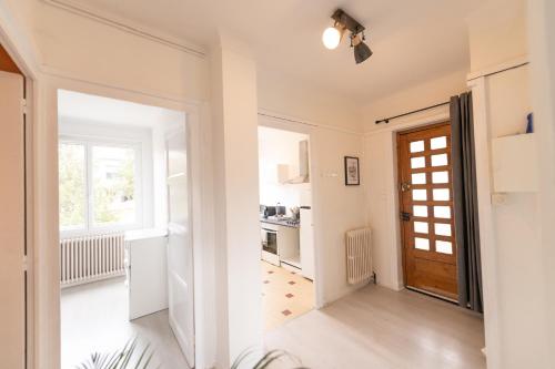 un couloir blanc avec une porte et une cuisine dans l'établissement KASA LYONNAISE - Proche Lyon, Transports, Tout équipé, à Grigny