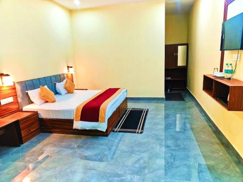 a hotel room with a bed and a flat screen tv at Divyam Resort in Barkot