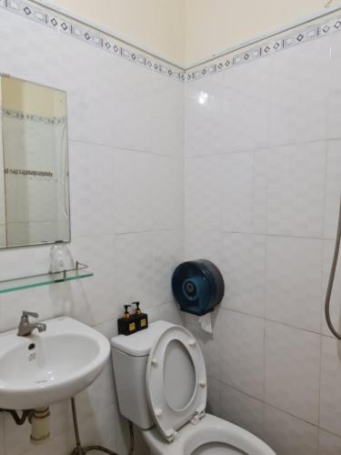 a white bathroom with a toilet and a sink at Tuan Thanh Homestay in Tân Hiệp